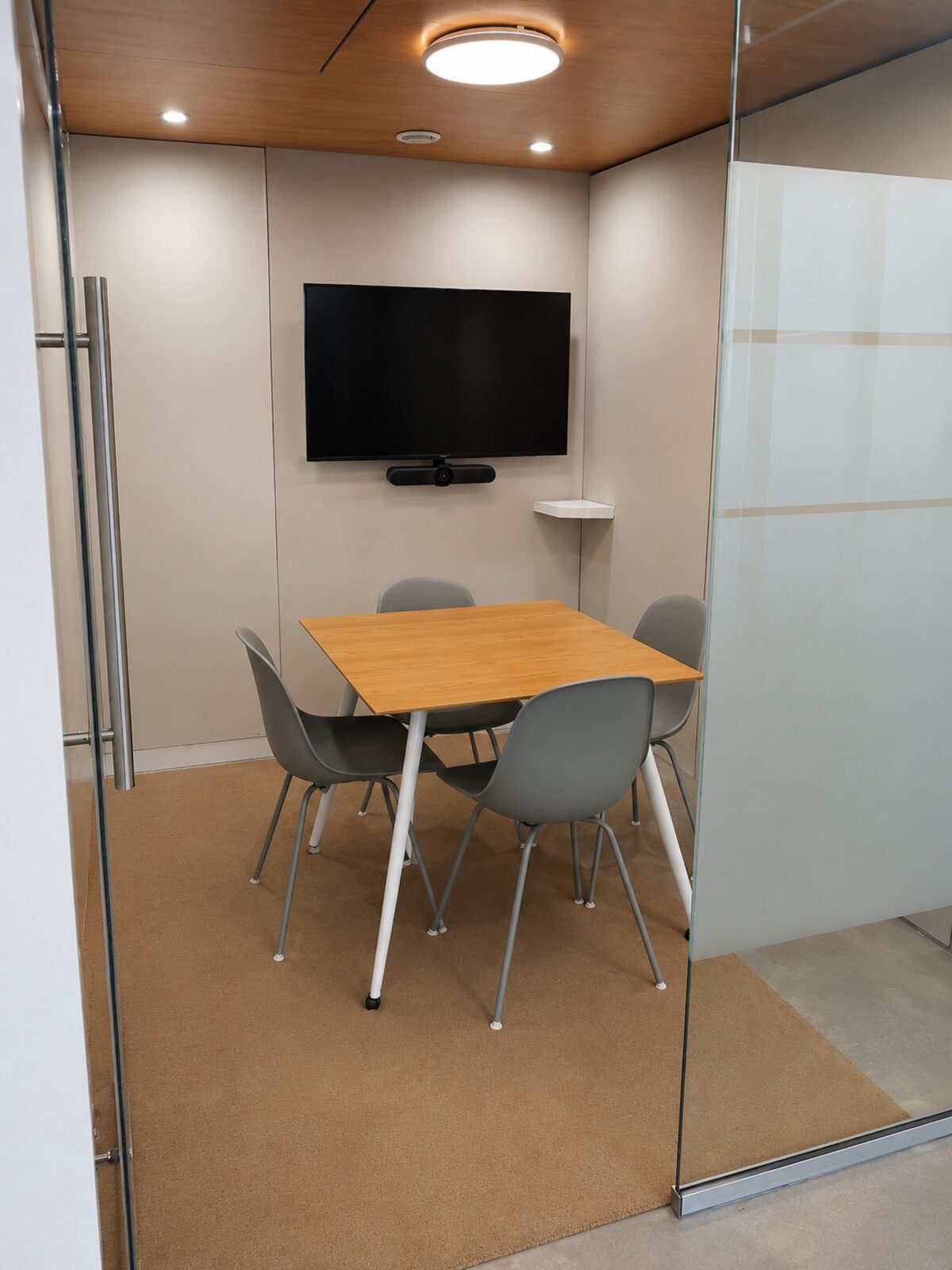 Tide Room private meeting room with video conferencing behind its glass door at Lyall Bay WorkHub Wellington